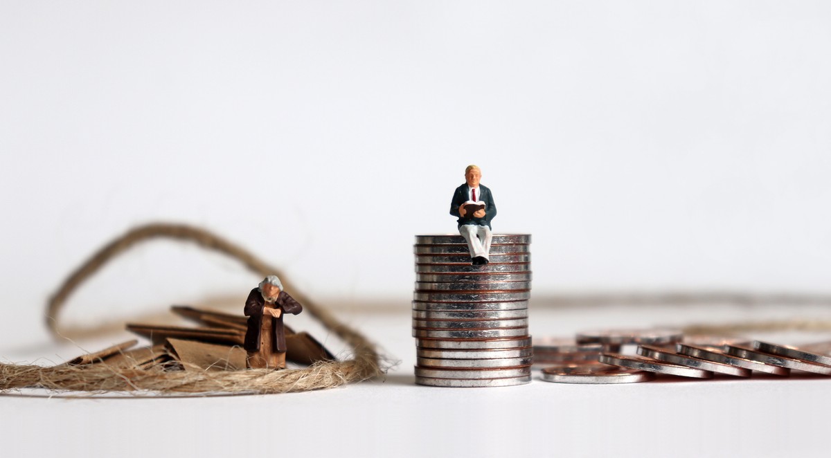 Pile of coins and miniature people. The concept of economic inequality in old age.