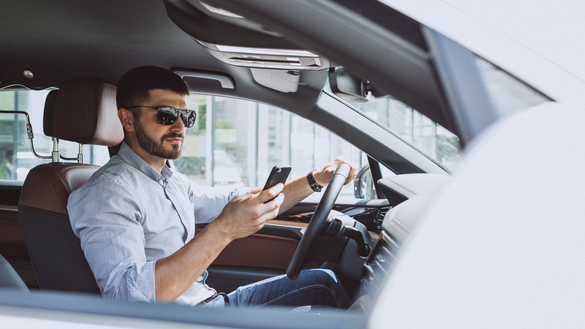 Mobilný telefón v ruke vodiča na parkovisku pred autoservisom, na obrazovke otvorená aplikácia Google Mapy s profilom dielne s priemerom 4,9 hviezdičky a tristo recenziami, vodič palcom posúva nadol zoznam hodnotení, kde vidno tri zhodne formulované päťhviezdičkové komentáre po sebe – ilustrácia typického vzorca kúpených fake recenzií na slovenskom trhu autoservisov. 
