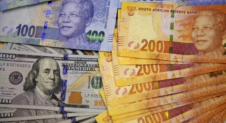 South African bank notes featuring images of former South African President Nelson Mandela (R) are displayed next to the American dollar notes in this photo illustration in Johannesburg August 13 2014.    REUTERS/Siphiwe Sibeko