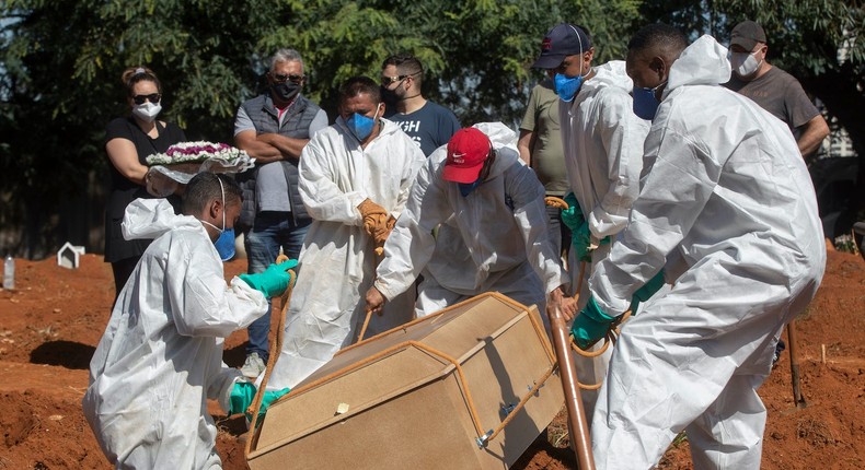 Cemetery workers in full protective gear lower a coffin that contain the remains of a person who died from complications related to COVID-19 at the Vila Formosa cemetery in Sao Paulo, Brazil, Wednesday, March 24, 2021.
