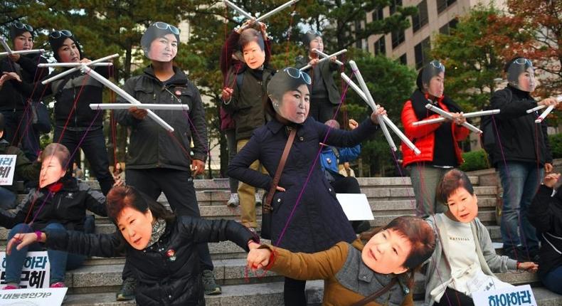 Protesters wearing masks of South Korean President Park Geun-Hye and her confidante Choi Soon-Sil rally in Seoul on October 29, 2016