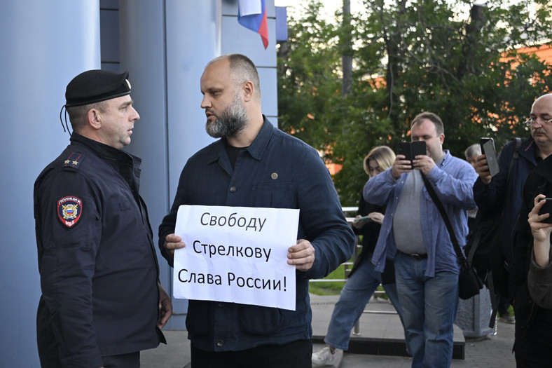 Paweł Gubarew, działacz "Klubu Wściekłych Patriotów", stoi z transparentem "Wolność dla Striełkowa. Chwała Rosji!" i rozmawia z funkcjonariuszem policji podczas pikiety przed sądem podczas przesłuchania Igora Girkina, 21 lipca 2023 r.