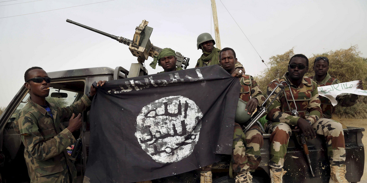 Nigerian soldiers hold up a seized Boko Haram flag after liberating Damasak, Nigeria, March 18, 2015.