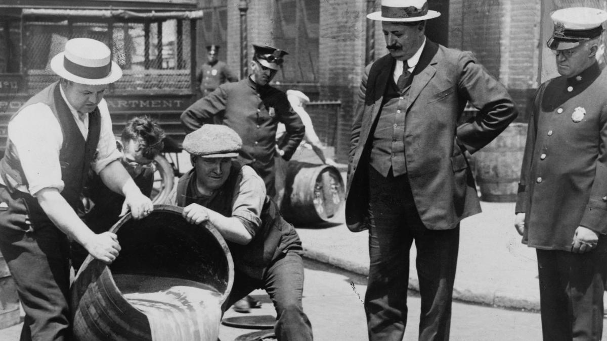 Prohibition in the USA 1920-1933: A barrel of confiscated illegal beer being poured down a drain. Al