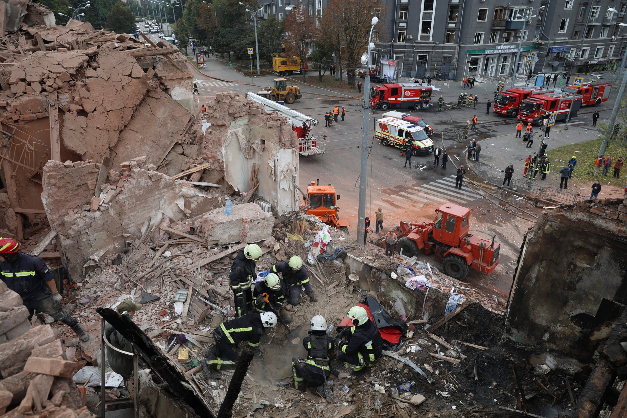 Príslušníci záchranných zložiek pátrajú po obetiach, ktoré prišli o život po raketovom útoku ruskej armády na viacposchodovú budovu v Charkove.