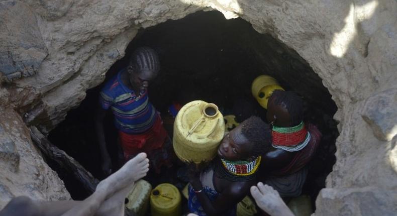 A young girl passes up a jerrycan filled with murky water trickling into a waterhole from underground rocks near Lokitaung in northern Kenya's Turkana county