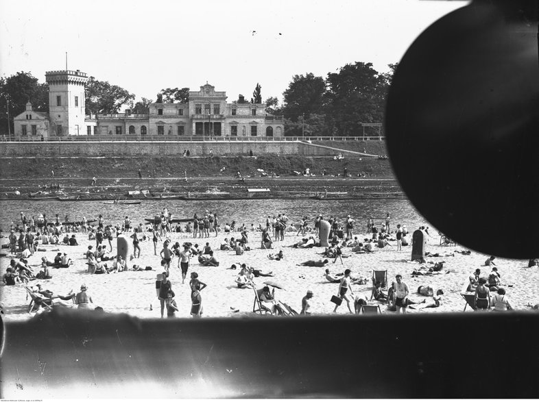 Plaża Towarzystwa Uniwersytetu Robotniczego w Krakowie. Plażowicze podczas wypoczynku. W tle widoczny pałac Lasockich (1933 r.)