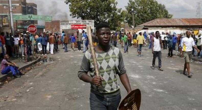 A local gestures as he holds a stick and a shield outside a hostel during anti-immigrant related violence in Johannesburg, April 17, 2015.