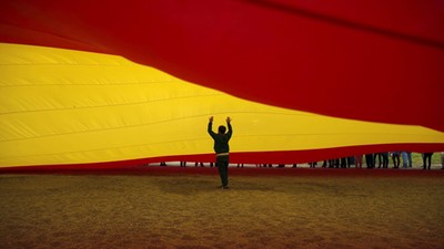 A child walks under a giant Spanish flag unfurled by supporters of Spain's Prime Minister Rajoy to s