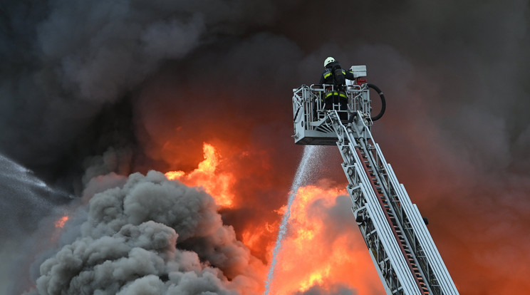 Létráról oltja a lángokat egy tűzoltó a XXIII. kerületben, ahol tűz ütött ki egy autóbontóban 2023. április 28-án / Fotó: MTI/Illyés Tibor