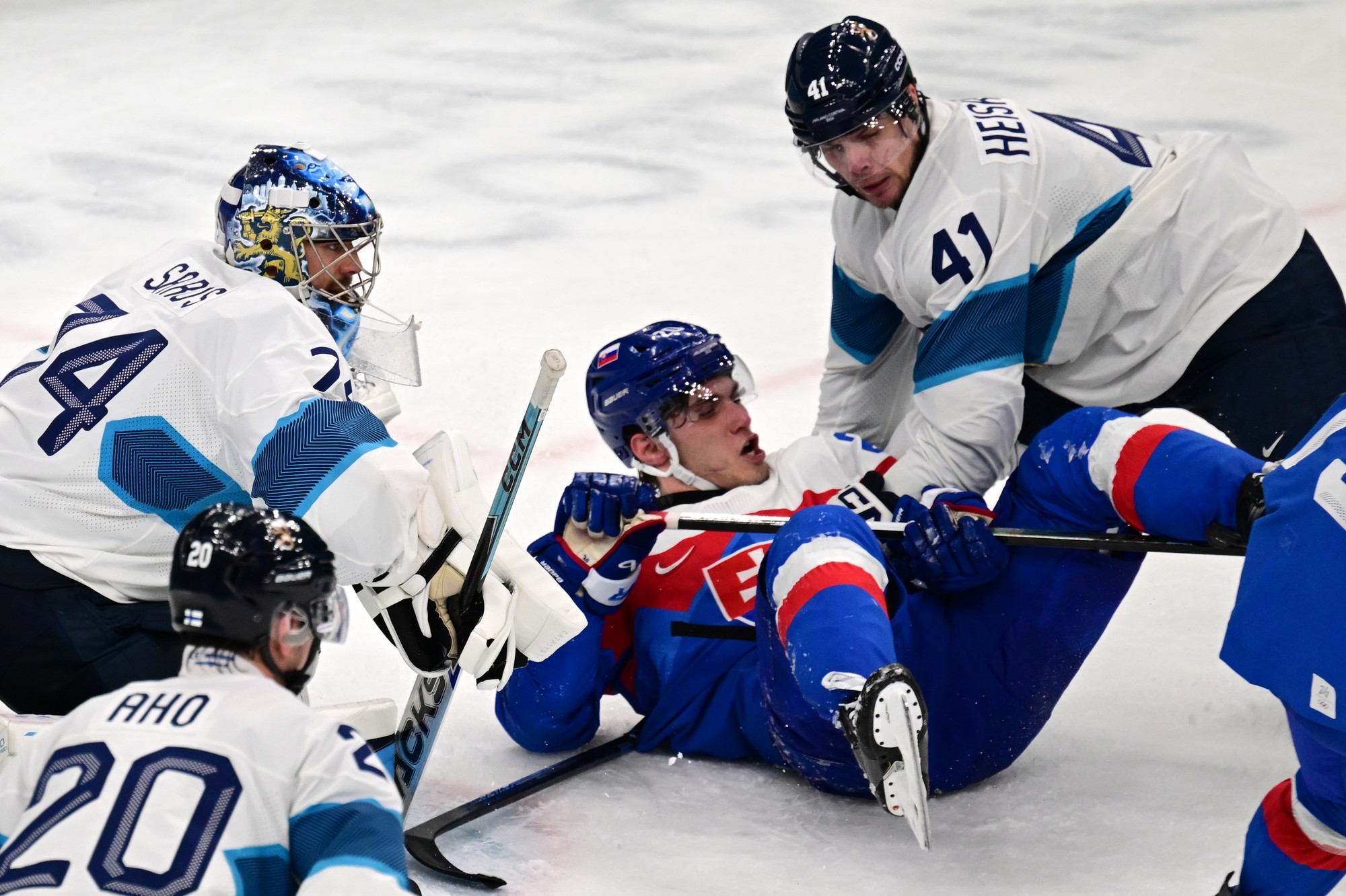 Slovenský hokejista Juraj Slafkovský (uprostred), hráči Fínska Sebastian Aho (20), brankár Juuse Saros (74) a Miro Heiskanen (41). 