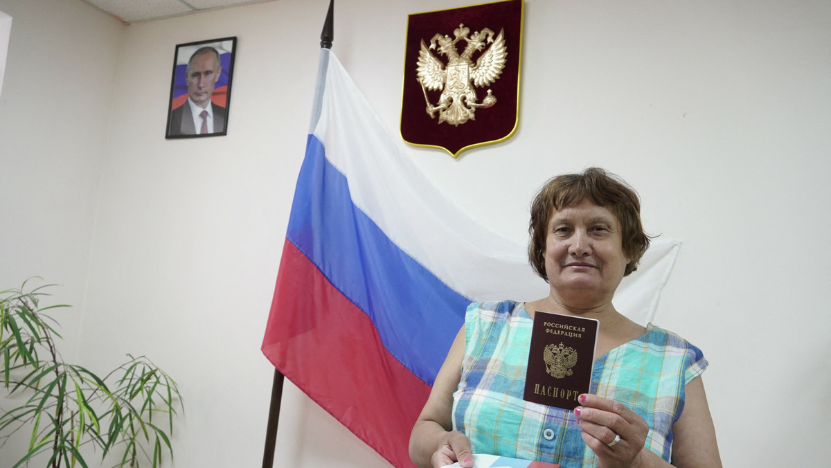 Gdy odbierają rosyjskie paszporty, ze ściany patrzy na nich Putin
