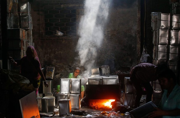 Workers clean used cooking oil tins in a recycling workshop in Mumbai