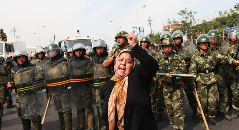 A Uighur woman protests in front of policemen at a street on July 7, 2009 in Urumqi, the capital of Xinjiang Uighur autonomous region, China.