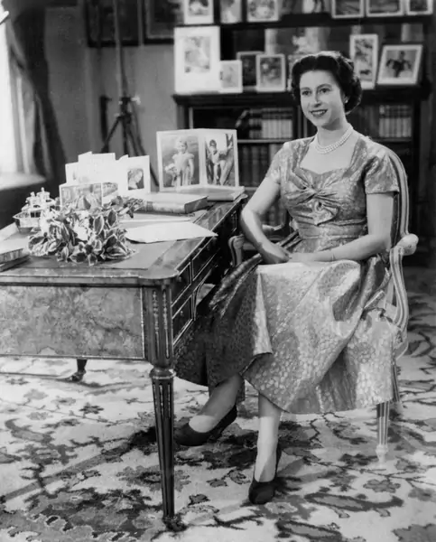 Królowa, w złotej sukience, jest widziana w Bibliotece w Sandringham krótko po tym, jak transmitowane były pierwsze w historii telewizyjne życzenia bożonarodzeniowe / Getty Images
