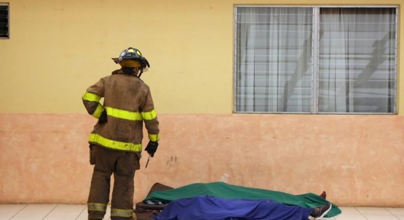 A firefighter looks at two victims at a government-run children's shelter in San Jose Pinula after fire swept the building east of Guatemala City