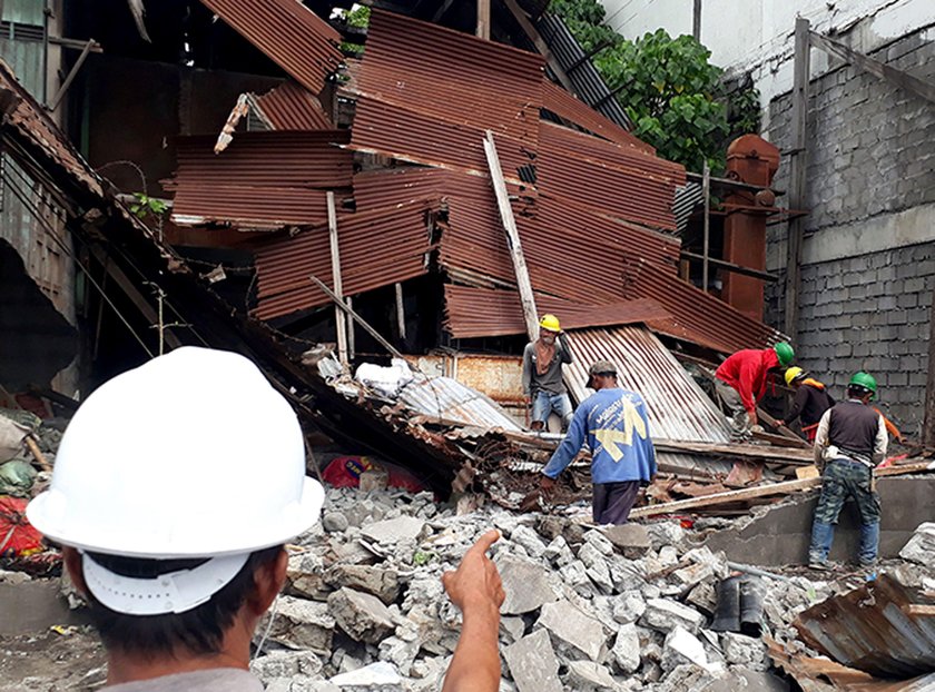 Workers clear concrete debris as they search for possible casualties at the ruins of an old building