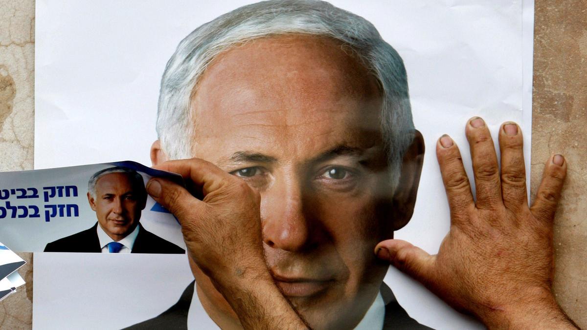 FILE PHOTO: A Likud party supporter puts up a poster depicting party leader Benjamin Netanyahu in th