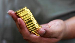 An employee holds gold pieces, each weighing 100 grams, at the state-owned mining company PT Antam Tbk metal refinery in Jakarta, July 13, 2012.REUTERS/Beawiharta
