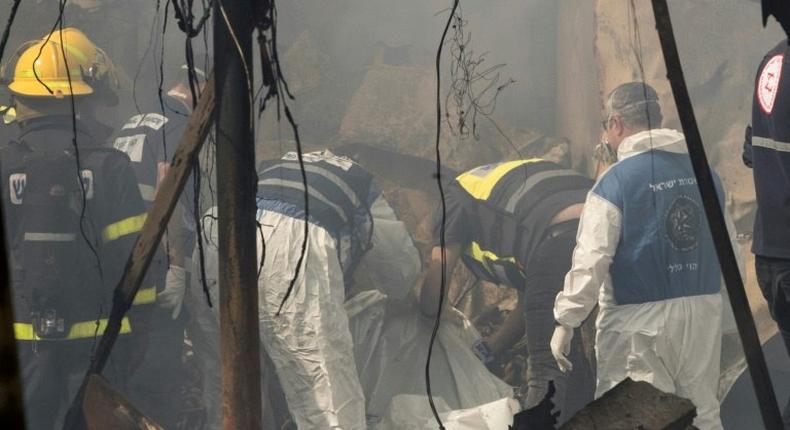 Rescue workers inspect a body after a fireworks warehouse blaze in the Israeli village of Porat on March 14, 2017