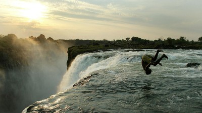 A Zambian man somersaults into a pool at the edge of the 110 metre high main falls of the Victoria F