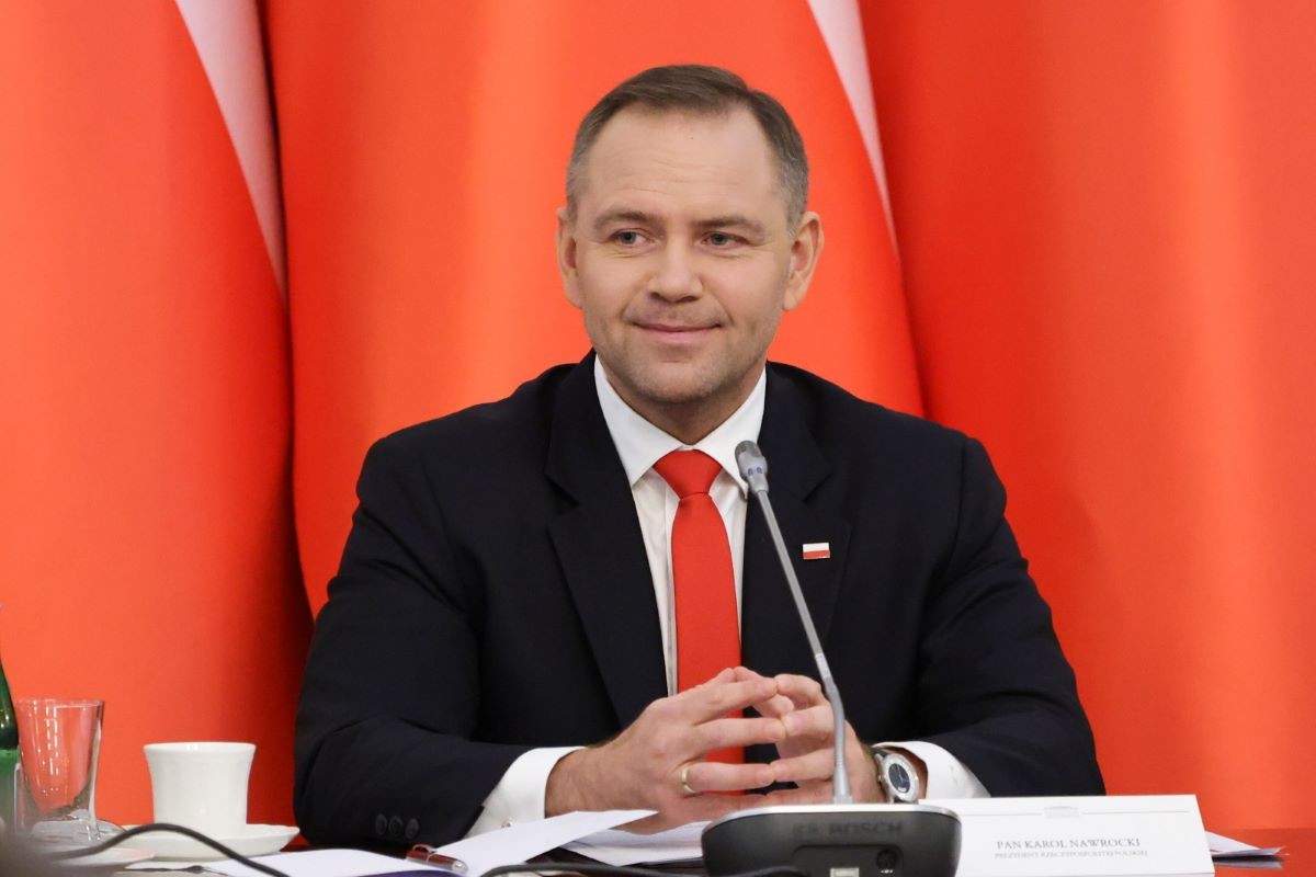 Prezydent RP Karol Nawrocki siedzi na tle flag Polski