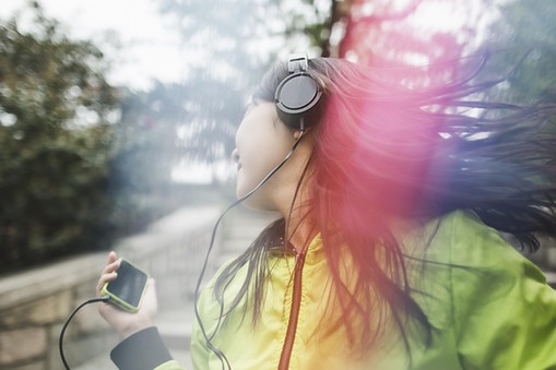 Young woman, outdoors, listening to music and dancing