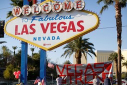 People sign a banner near the Welcome to Fabulous Las Vegas sign following the Route 91 music fest