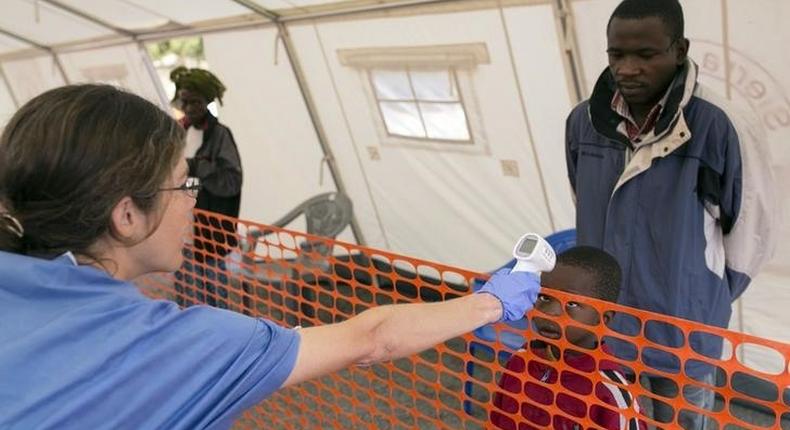 A health worker checks the temperature of a boy at the entrance to a Red Cross facility in the town of Koidu, Kono district in Eastern Sierra Leone December 19, 2014. 