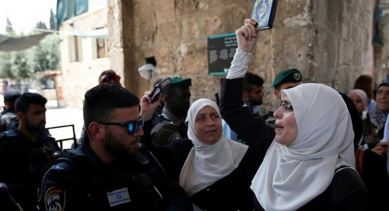 A Palestinian protester holds a copy of the Koran and shouts slogans in front of Israeli security forces during a demonstration in Jerusalem's Old City on July 20, 2017