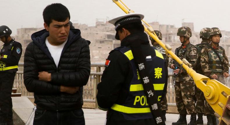 A police officer checks a Uighur man's ID documents in Kashgar, Xinjiang, in March 2017.