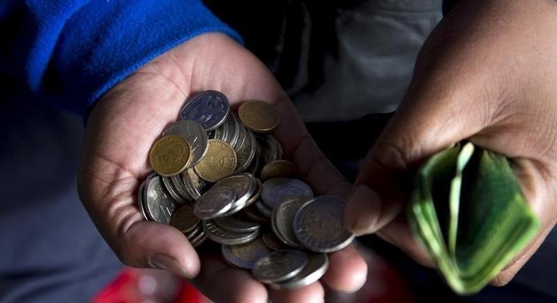 A street trader counts out change for a customer in Durban, September 8, 2015. 