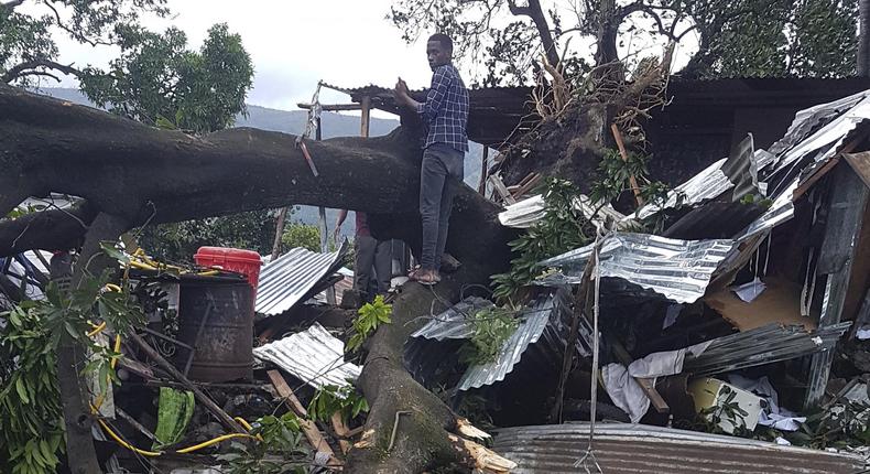 A man stands on fallen trees which damaged his home in Moroni, Comoros, Thursday. (The Spokesman-Review)