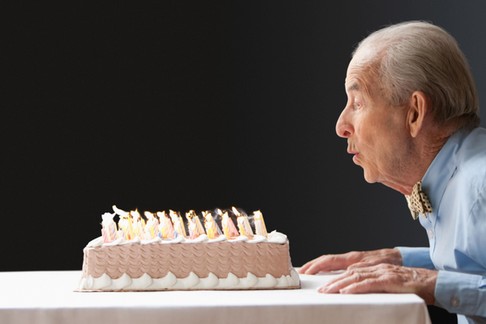 Senior Hispanic man blowing out birthday candles