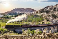 Glenfinnan Railway Viaduct in Scotland with the Jacobite steam train against sunset over lake