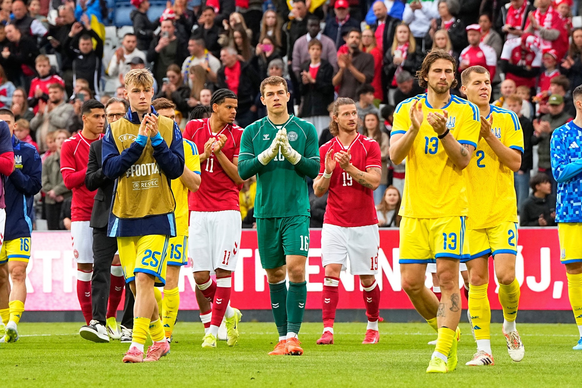 Hráči dánskeho a ukrajinského tímu kráčajú po tom, čo bol predčasne ukončený prípravný futbalový zápas Dánsko - Ukrajina pre kolaps dánskeho futbalistu Christiana Eriksena.