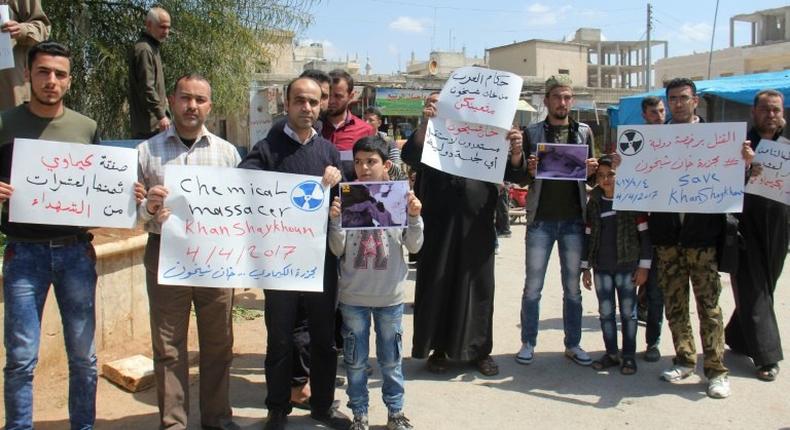 Residents of Khan Sheikhun in northern Syria hold placards and pictures on April 7, 2017 during a protest condemning a suspected chemical weapons attack on their town earlier this week that killed at least 87 people