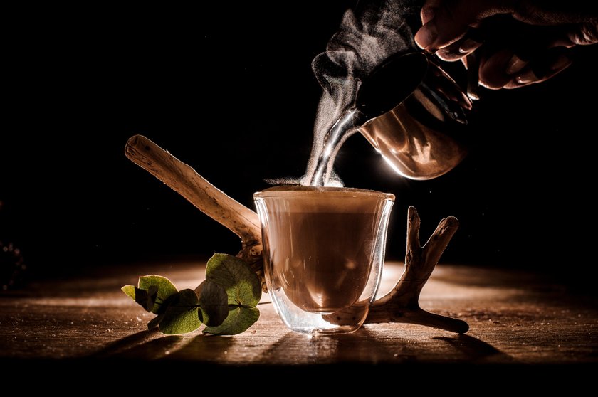 Male hand pouring water from pitcher into the coffee cup