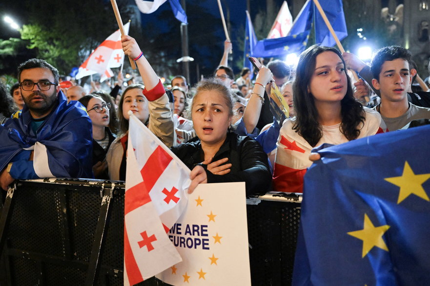 Protestujący trzymają gruzińskie i europejskie flagi podczas demonstracji przed budynkiem parlamentu w Tbilisi, 17 kwietnia 2024 r.
