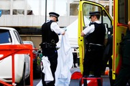 Police officers unfold a sheet infront of a body covered with a blanket after the London Ambulance Service reported that a man collapsed and died from a heart attack in the Mayfair district of central London