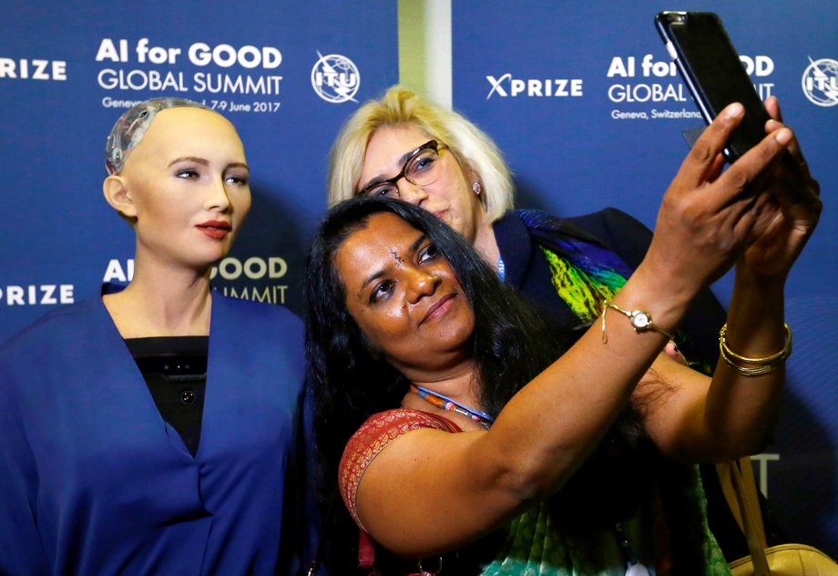 Attendees pose with Sophia, a robot integrating the latest technologies and artificial intelligence developed by Hanson Robotics during a presentation at the "AI for Good" Global Summit in June 2017.