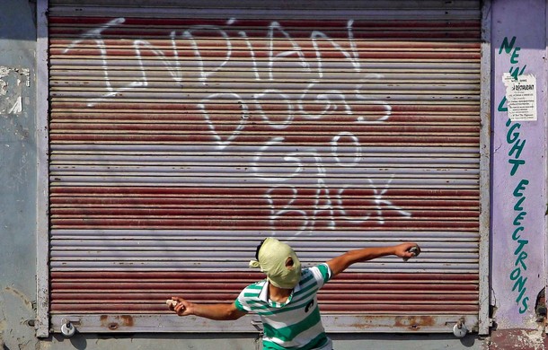 A demonstrator hurls a stone at Indian policemen during anti-India protest in Srinagar