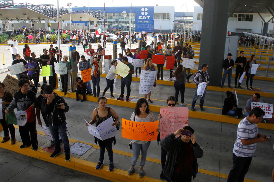 Demonstrators hold signs as they allow duty-free access for vehicles during a protest against the rising prices of gasoline enforced by the Mexican government in El Chaparral, on the border crossing between the US and Mexico, in Tijuana, Mexico, January 8, 2017.
