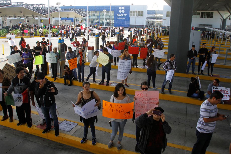 Demonstrators hold signs as they allow duty-free access for vehicles during a protest against the rising prices of gasoline enforced by the Mexican government in El Chaparral, on the border crossing between the US and Mexico, in Tijuana, Mexico, January 8, 2017.