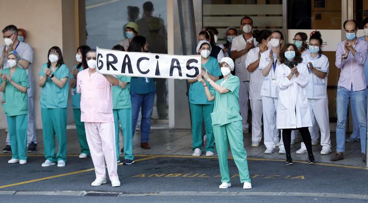 Egészségügyi dolgozók megtapsolják a munkájukért az ablakokban és az erkélyeken köszönetet mondó embereket a valenciai La Fe kórház előtt 2020. május 17-én, a koronavírus-járvány idején