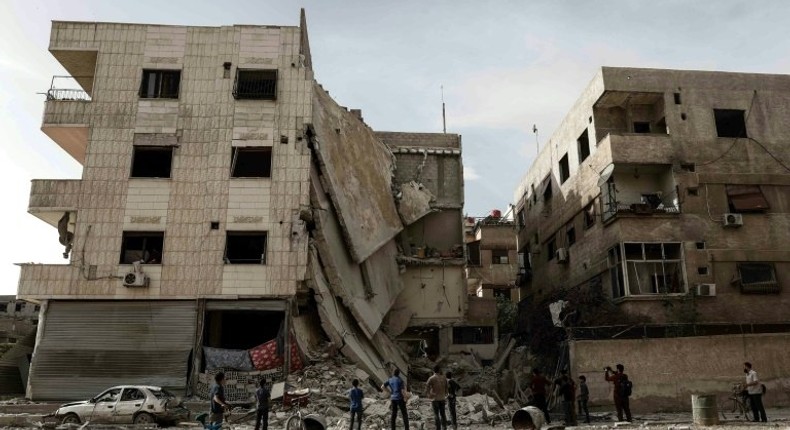 People inspect a hospital, damaged following an air strike a rebel-controlled town in the eastern Ghouta region on the outskirts of the capital Damascus on May 1, 2017