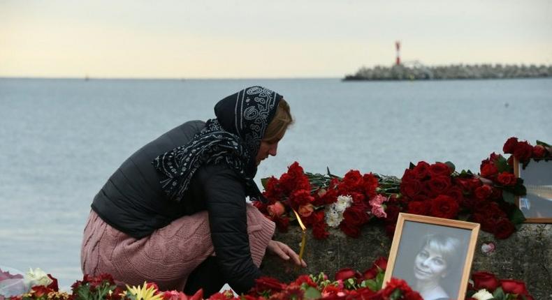 A woman lights a candle at a memorial to one of the victims of the Black Sea plane crash, famous Russian charity activist and founder of the Voters' League Yelizaveta Glinka, on the shores of the Black Sea in Sochi on December 27, 2016