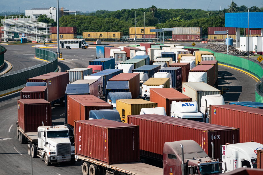 Ciężarówki przewożące kontenery ustawiają się w kolejce do punktu kontrolnego w porcie Manzanillo w Meksyku.
