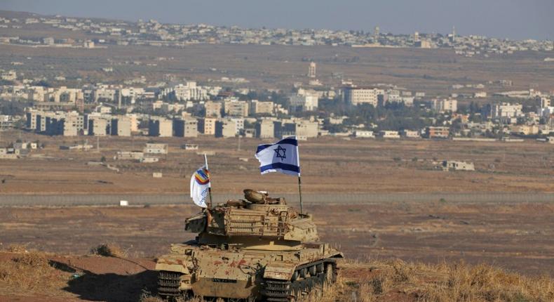 An Israeli flag flutters over the wreckage of an Israeli tank overlooking the armistice line on the Golan Heights