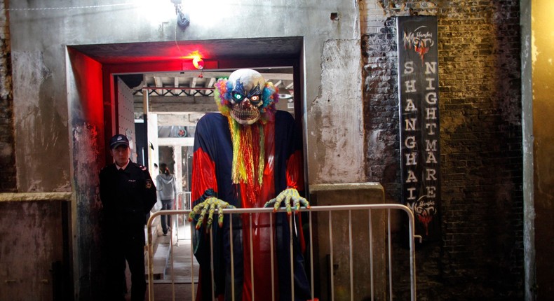 A costumed performer beside a security guard at the gate of the Shanghai Nightmare haunted house attraction in Shanghai in 2010.